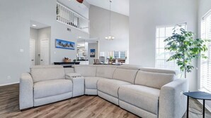 Ein geräumiges Wohnzimmer mit einer großen Eckcouch, einem Essbereich und einer Treppe, die in eine obere Etage führt.