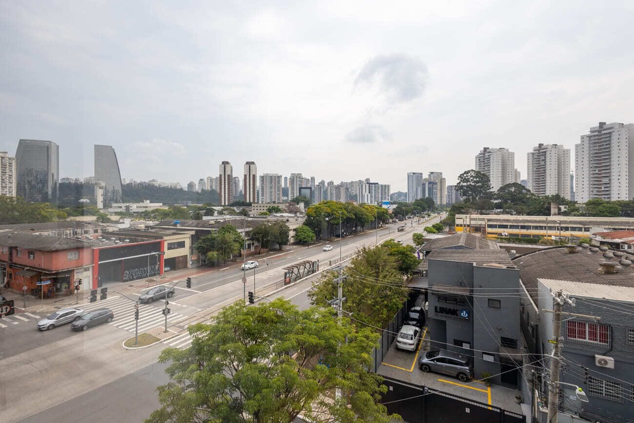 Paisagem urbana com edifícios altos, rua movimentada e um elétrico.