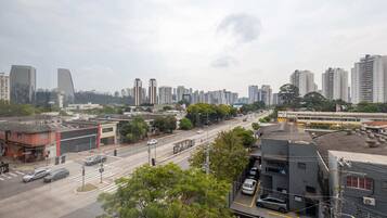 Paisagem urbana com edifícios altos, rua movimentada e um elétrico.