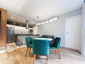 A modern kitchen with a refrigerator, microwave, and a dining area with a round table and four chairs. - 360 Nações Unidas (São Paulo)
