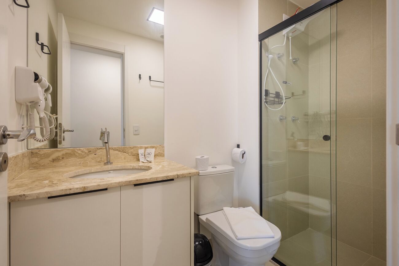 A modern bathroom with a marble sink, a glass-enclosed shower, and a toilet.