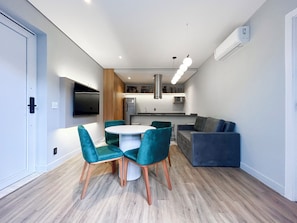 A modern kitchen with a dining area, a sofa, and a TV mounted on the wall. - 360 Nações Unidas (São Paulo)
