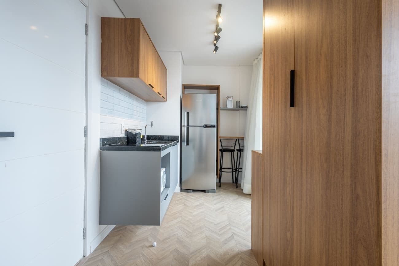 Una cucina moderna con pavimento a spina di pesce, mobili in legno e frigorifero in acciaio inossidabile.