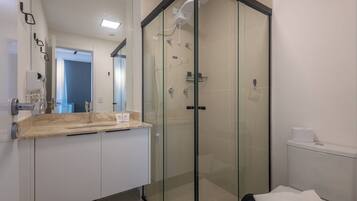 Un baño moderno con ducha de vidrio, tocador de madera y retrete.