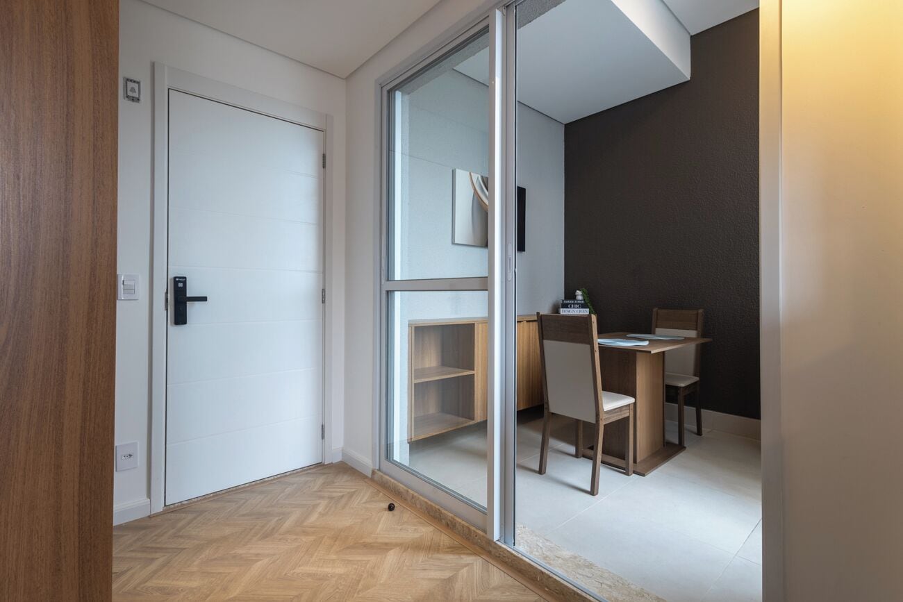 A room with a sliding glass door leading to a dining area with a table and chairs.