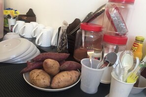 A table with plates of food, utensils, and containers. - Kuree Hut (Semporna)