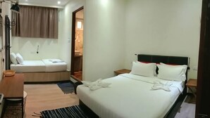A hotel room with a bed, a desk, a chair, a lamp, and a window.