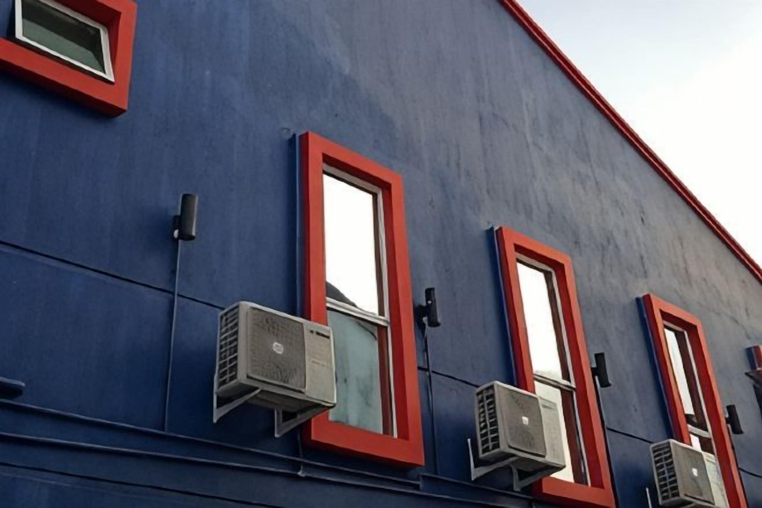 A building facade with air conditioning units and red-framed windows.