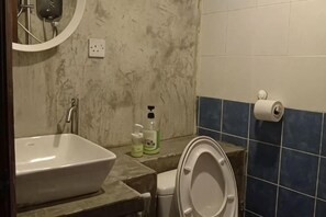 A bathroom with a sink, toilet, and a mirror. - Kuree Hut (Semporna)