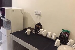 A coffee station with a water dispenser, coffee cups, and a coffee grinder. - Kuree Hut (Semporna)