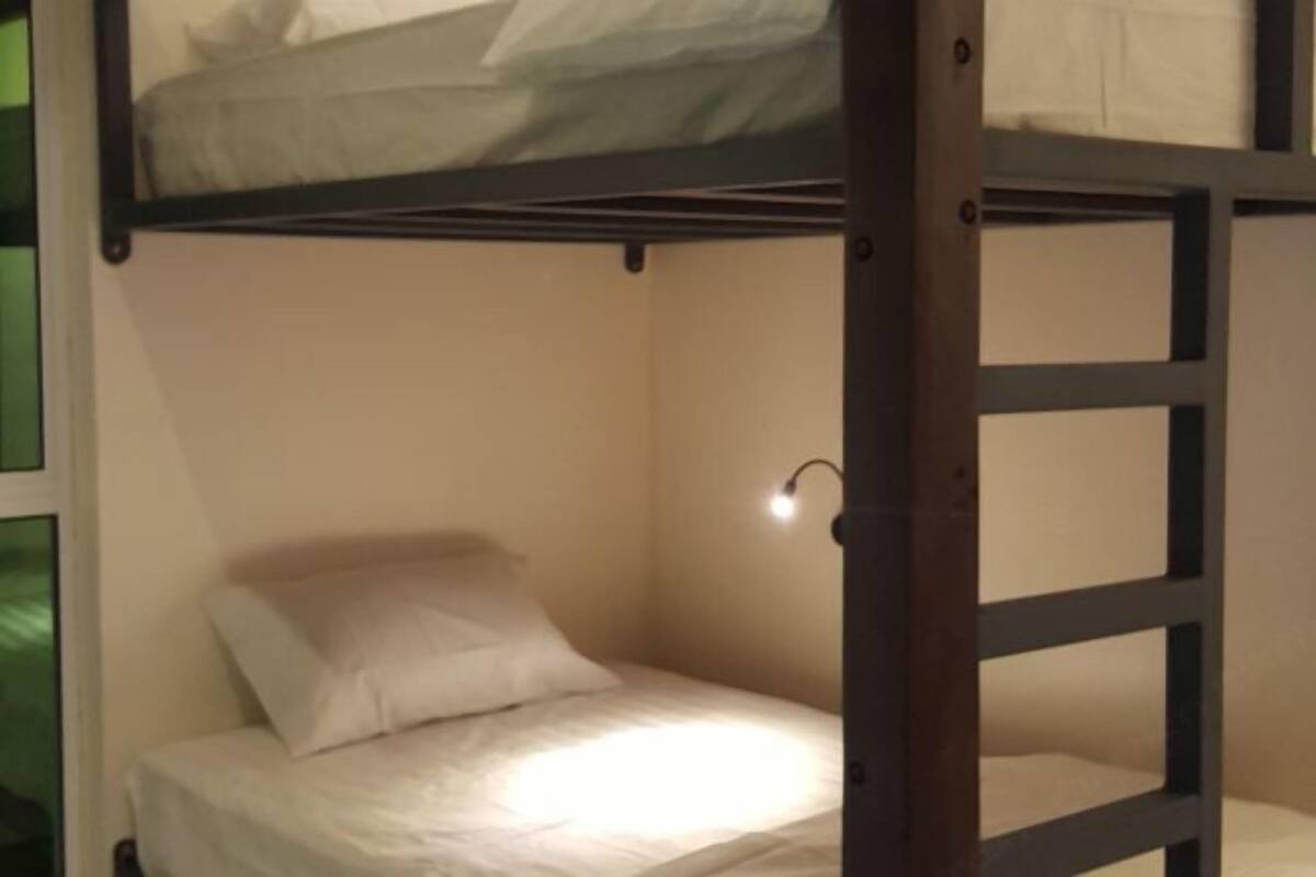 A bunk bed with a single bed below and a top bunk with a light fixture.