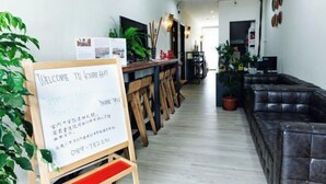 A reception area with a welcome sign, wooden chairs, a leather sofa, and potted plants.