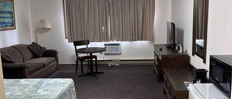 Una habitación de hotel con cama, sofá, escritorio, televisor y refrigerador.