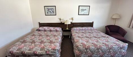 A twin room with two single beds, a wooden headboard, a desk with a lamp, and a chair.