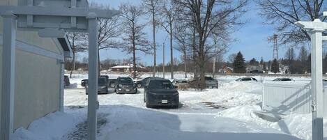 Un estacionamiento techado con nieve en el suelo y varios coches aparcados.