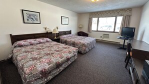 A hotel room with two beds, a desk, a television, and a window with curtains. - Auberge Eldo Inn (Blind River)