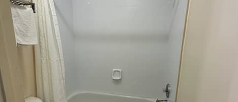 A small, white bathroom with a toilet, a bathtub, and a shower curtain.