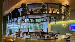 A bar area with a wooden ceiling, hanging plants, and a TV screen. - Get a Flat 1910 - Jardim Paulista (São Paulo)