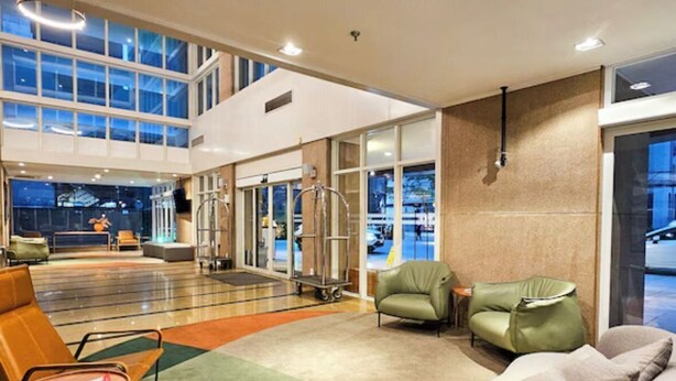 A modern lobby with a seating area, a reception desk, and a glass door entrance. - Get a Flat 1910 - Jardim Paulista (São Paulo)