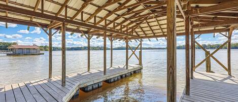 A wooden dock with a covered pavilion, extending over a body of water.