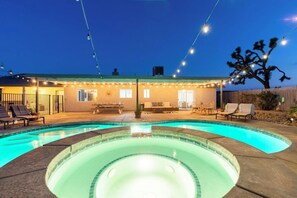 A swimming pool with a hot tub in the center, surrounded by lounge chairs and a covered patio area. - Yucca Valley Oasis: Pool, Spa & Game Room Retreat (Yucca Valley)