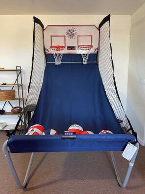 A home basketball hoop with a scoreboard, a blue padded backboard, and multiple basketballs.