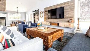 A modern living room with a sofa, a coffee table, and a TV mounted on the wall. - Sun Mesa Poolside Hideaway | Spa | Game Room | NEW, Sun Mesa Poolside Hideaway | Spa | Game Room | N (Yucca Valley)