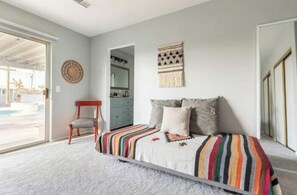 A bedroom with a bed, a chair, a window, and a door.