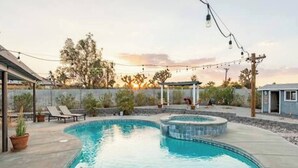 A backyard with a swimming pool, lounge chairs, and string lights. - Sun Mesa Poolside Hideaway | Spa | Game Room | NEW, Sun Mesa Poolside Hideaway | Spa | Game Room | N (Yucca Valley)