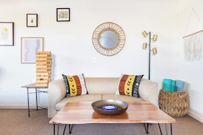 A living room with a sofa, a coffee table, a wall-mounted mirror, and a floor lamp.