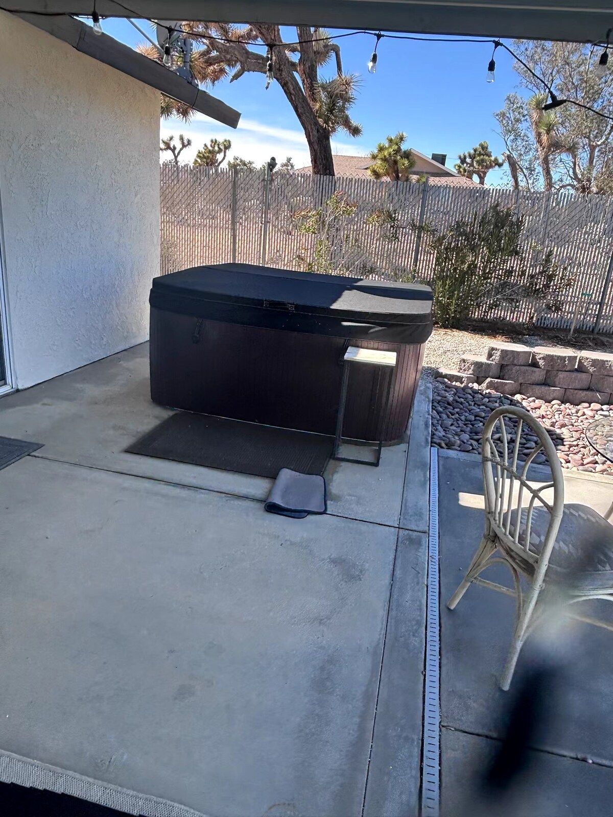 A patio area with a hot tub, a chair, and a concrete floor.
