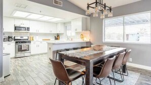 A modern kitchen with white cabinets, a central island, and a chandelier. - Sun Mesa Poolside Hideaway | Spa | Game Room | NEW, Sun Mesa Poolside Hideaway | Spa | Game Room | N (Yucca Valley)