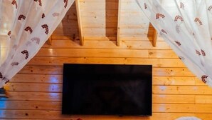A cozy room with a bed, a flat-screen TV, and wooden walls.
