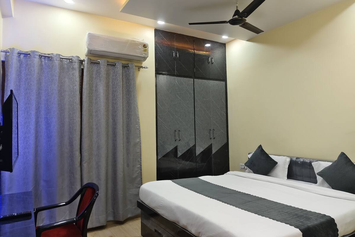 A bedroom with a bed, a wardrobe, a ceiling fan, and an air conditioning unit.