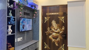 Uma sala de estar moderna com televisão na parede, um violão e flores decorativas.