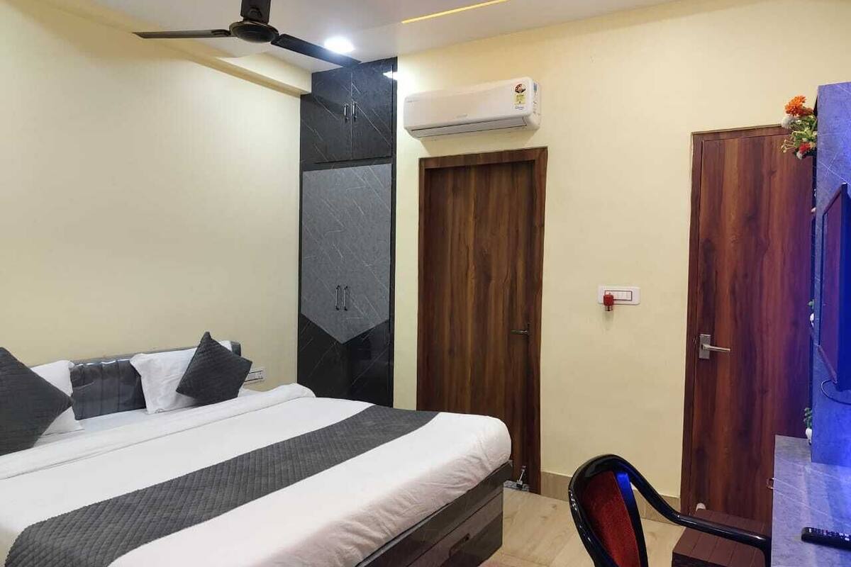 A bedroom with a bed, a wardrobe, an air conditioning unit, and a door.