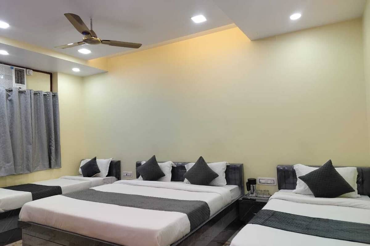 A hotel room with four single beds, a ceiling fan, and a large window with curtains.