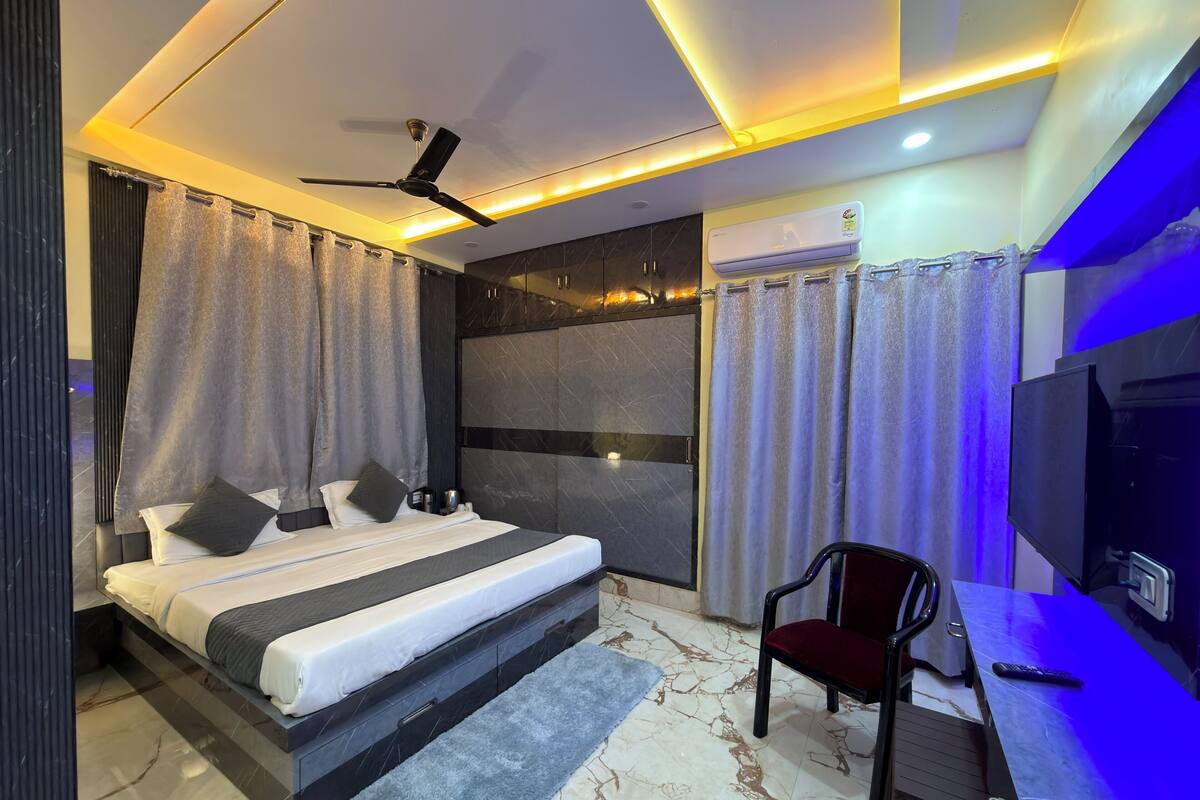 A modern bedroom with a bed, a desk, a chair, a ceiling fan, and an air conditioning unit.