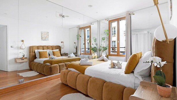 Une chambre d’hôtel moderne avec un grand lit, un petit canapé, une table à manger et un miroir.