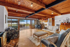 Un espacio habitable amplio con techo de madera, un sofá grande, una mesa de centro y vistas al exterior.