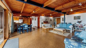 A spacious living area with wooden beams, a dining set, a sofa, and a bookshelf. - Lakefront Retreat - Lake Taupo Holiday Home (Tauranga Taupo)