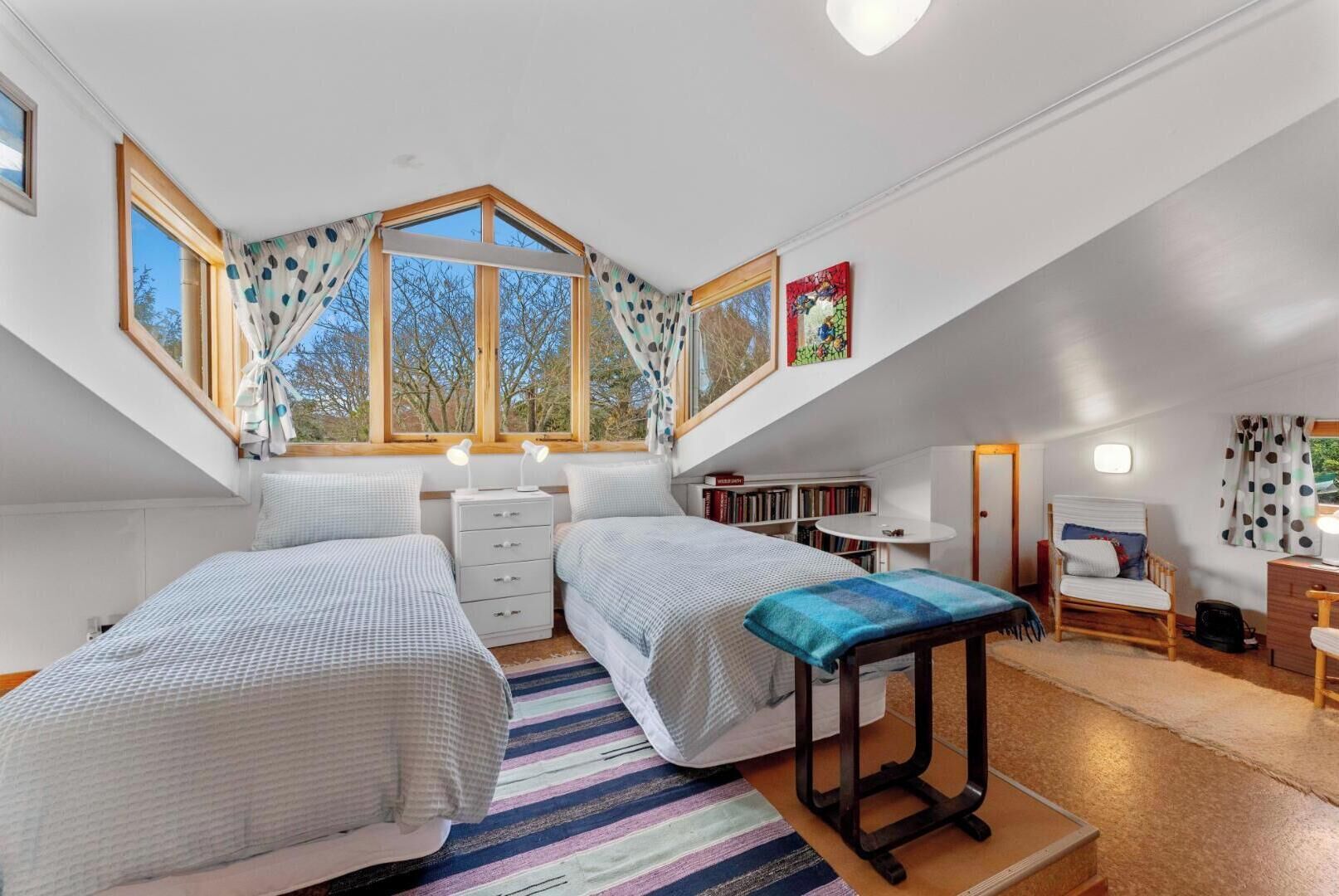 Een slaapkamer met twee bedden, een bureau, een stoel en een raam met gordijnen.