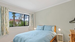 A bedroom with a bed, a nightstand, a dresser, and a window with curtains. - Birch Cottage - Greytown Holiday Home (Greytown)
