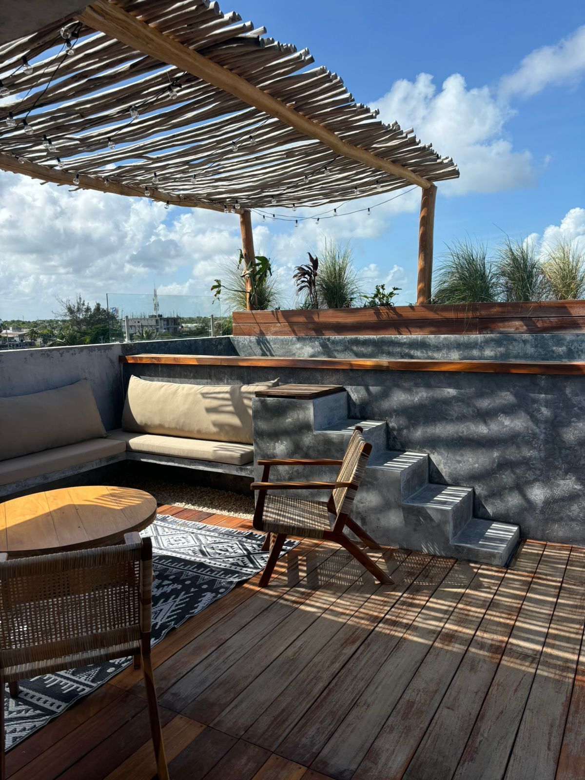 Una terraza en la azotea con una pérgola de madera, mobiliario exterior y vistas del horizonte de la ciudad.