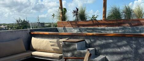 Una terraza en la azotea con una pérgola de madera, mobiliario exterior y vistas del horizonte de la ciudad.