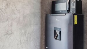 A black minibar refrigerator with a microwave on top, a door handle, and a yellow sticker on the right side. - #2 Down Town Loft with pool in the heart of Cancun (Cancún)