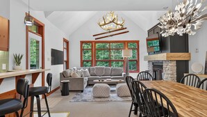 Ein modernes Interieur mit Essbereich, Sofa, Kamin und großen Fenstern.