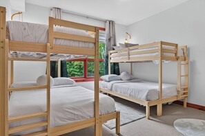 A bunk bed room with a window, a small table, and a rug. - 205 Les Eaux Unit 7 (Mont-Tremblant)