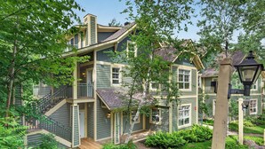 Ein mehrstöckiges Haus mit Veranda, Treppe und Garten mit Steinen und Pflanzen.