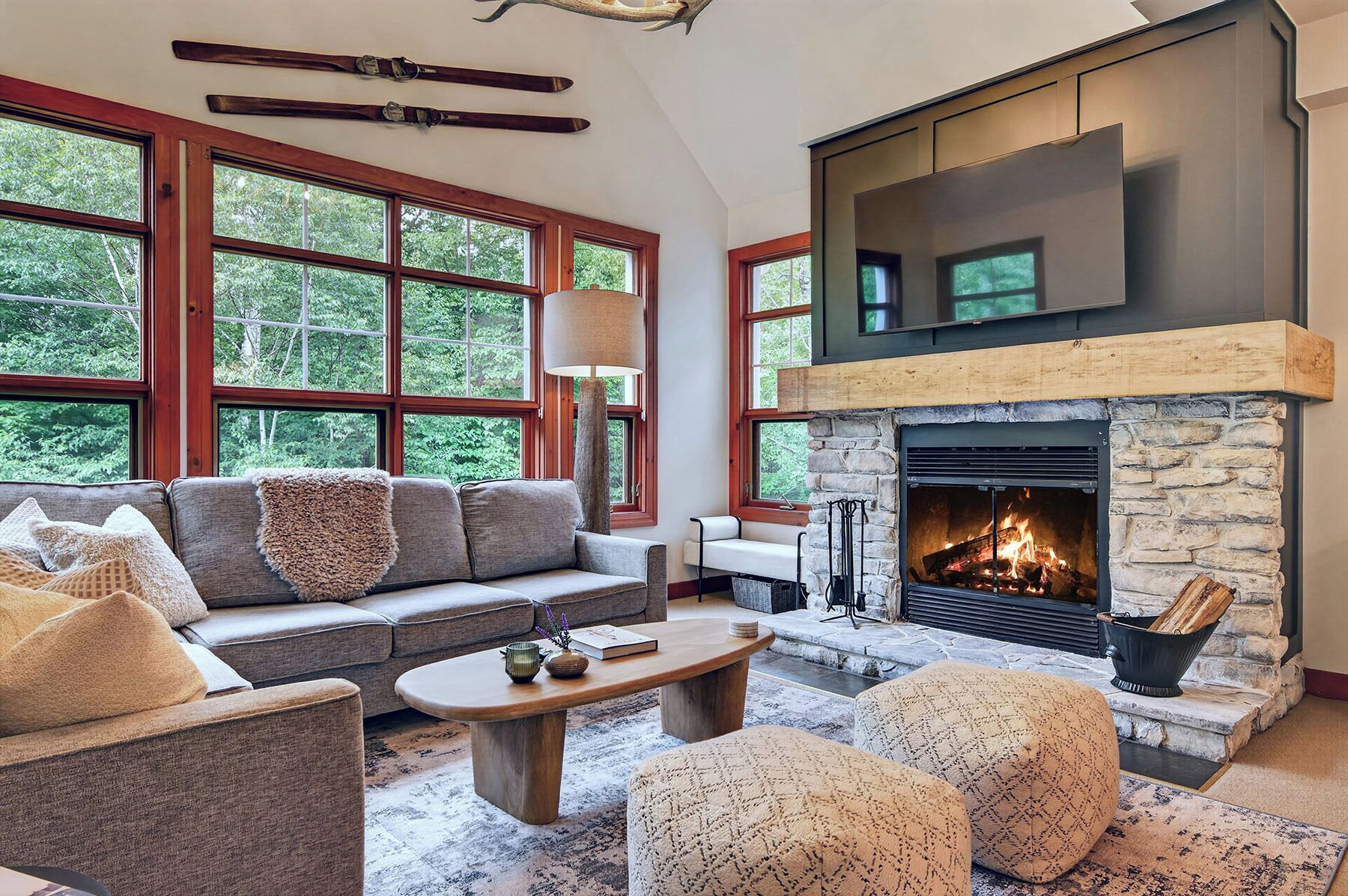 Una sala de estar acogedora con chimenea de piedra, ventanas amplias, un sofá y una mesita de centro.